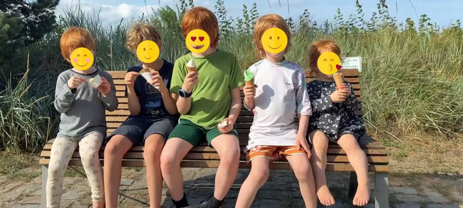 Kinder essen Eis auf einer Bank.